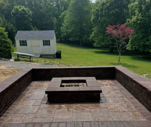 Stamped concrete patio with raised seating wall and square gas fire pit