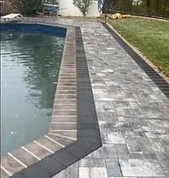 Paver pool deck with a contrasting dark border running alongside the pool